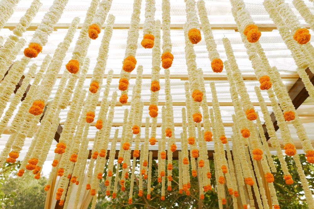 Decorative ceiling installation with hanging orange lanterns and white fabric creating an ethereal canopy.
