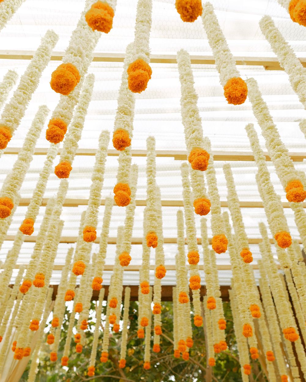 Artistic overhead view of orange paper lanterns suspended from white fabric draped ceiling.