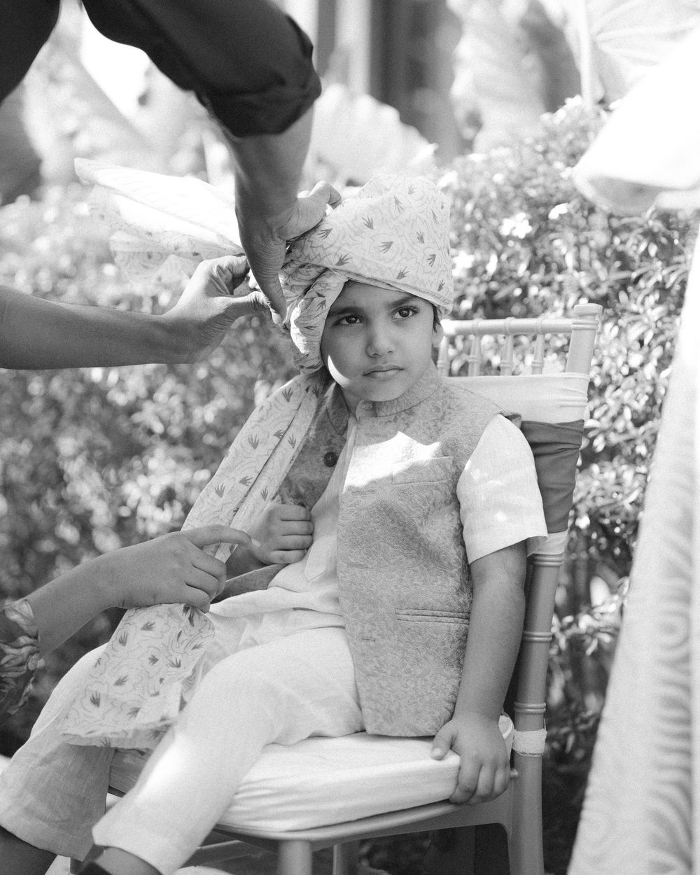 Young child sitting in a garden chair during an outdoor photoshoot.