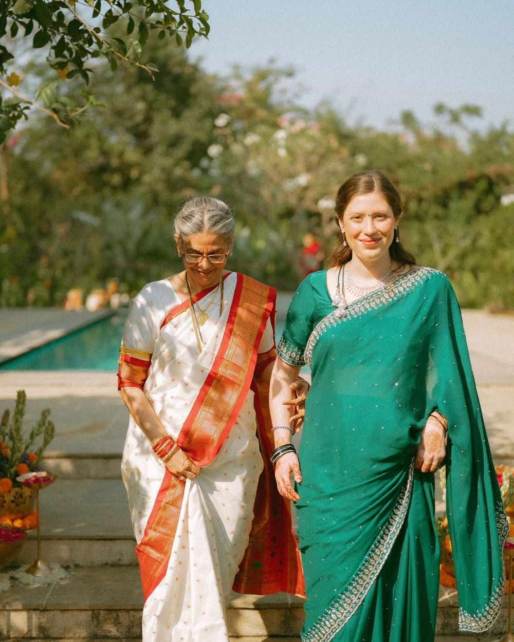 Outdoor gathering showing people dressed in traditional Indian clothing including green sari and white kurtas.