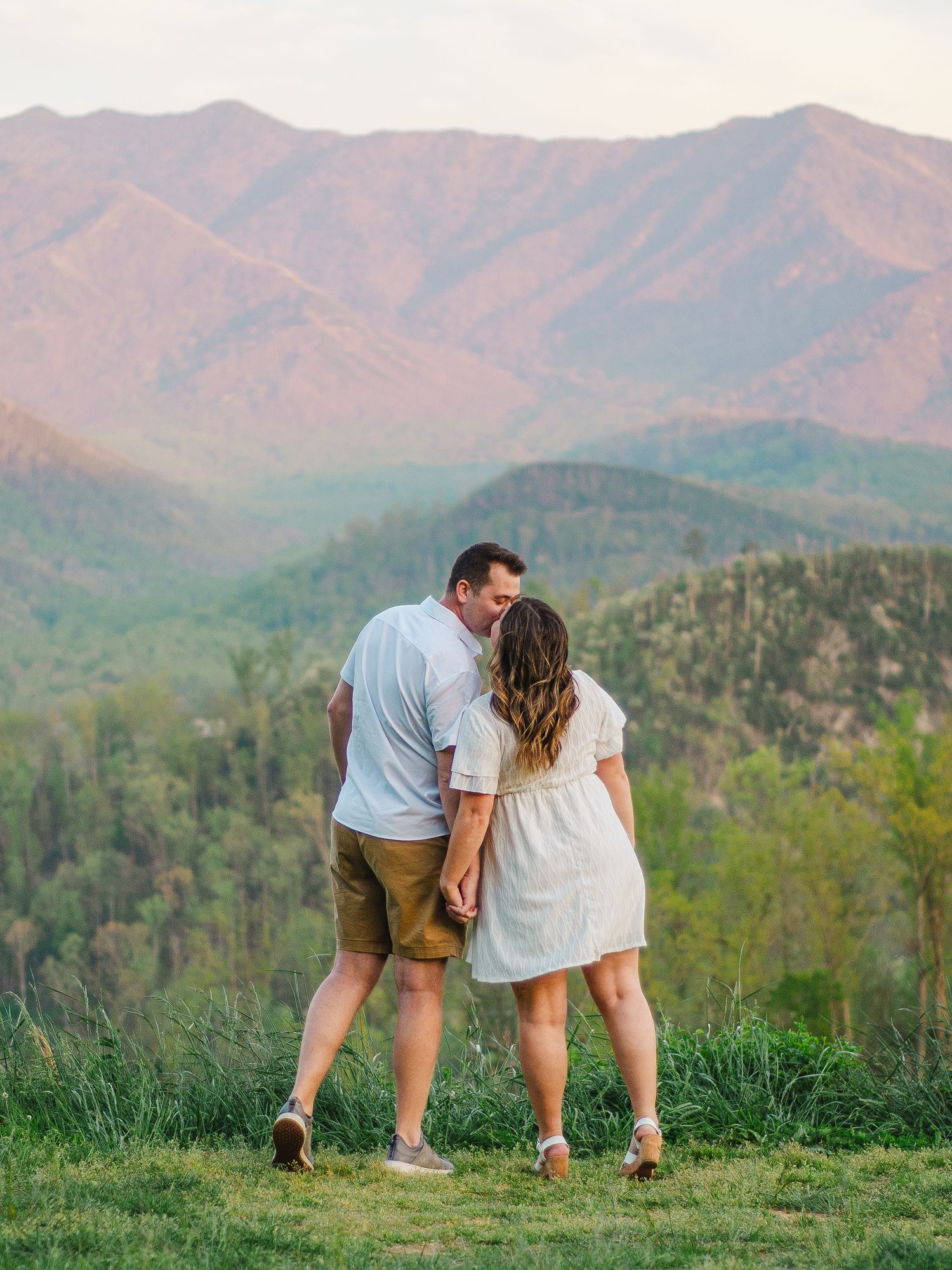 Two people posing playfully in casual attire against a scenic mountain backdrop in the Great Smoky Mountains.