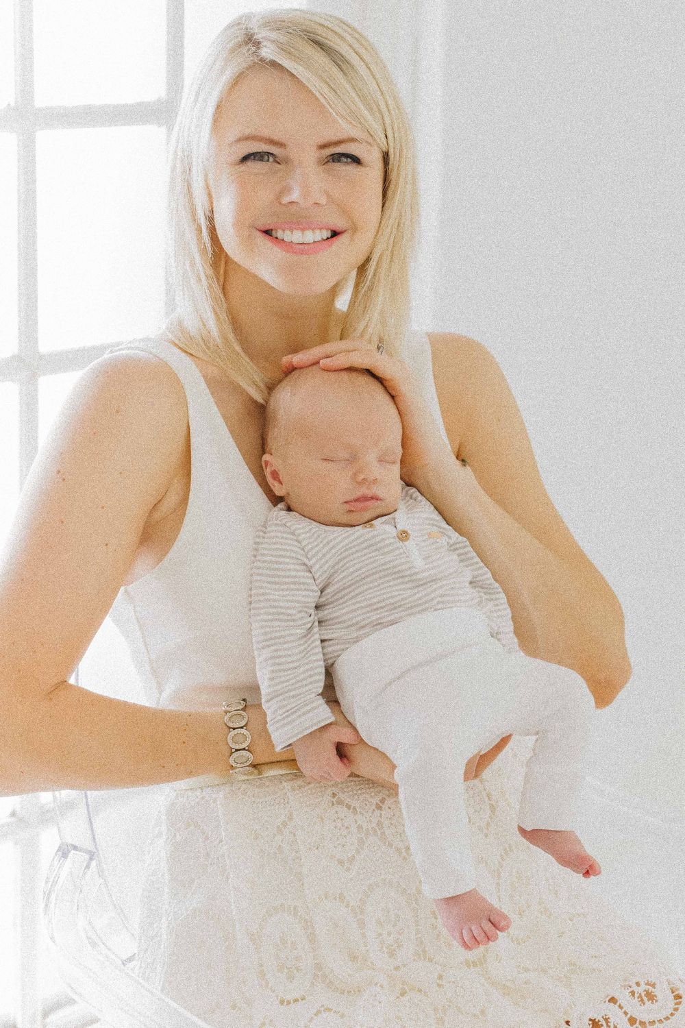 Mother and newborn portraits in white lace dress against bright window lighting. Fotografia profissional de maternidade, recém-nascido.