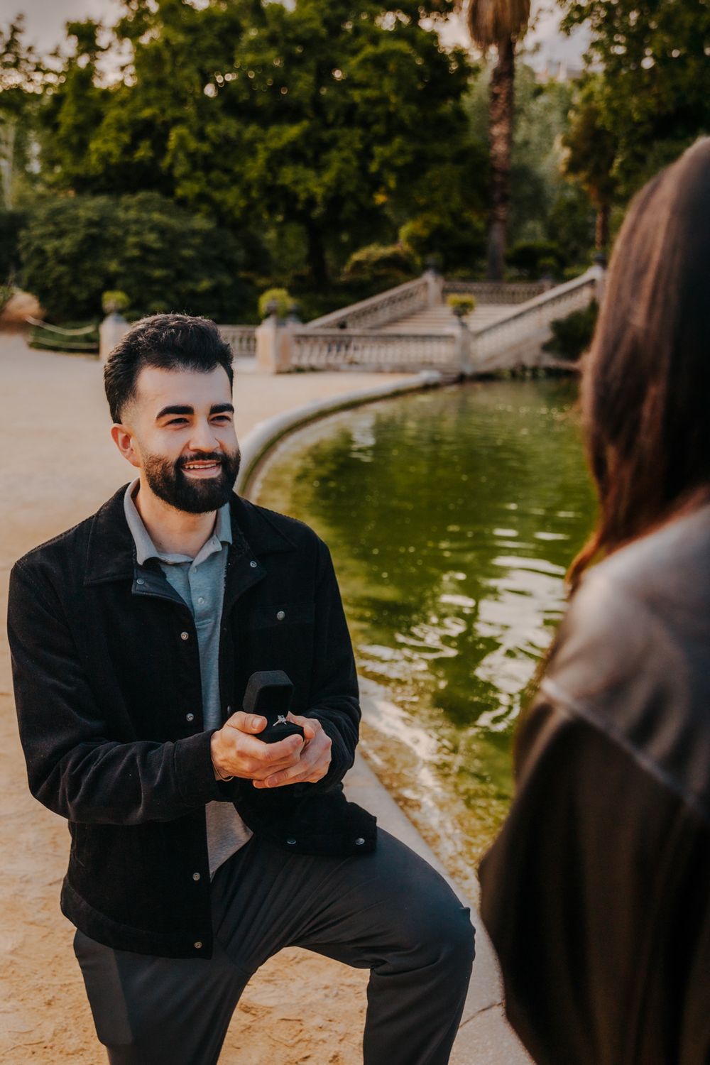 Proposal moment framed by park trees and warm light.