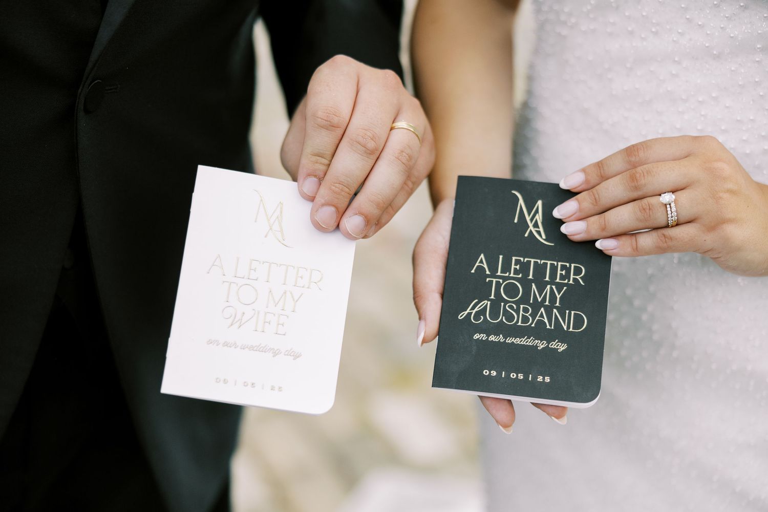 Two hands hold wedding-themed paper items including a white card and a dark green 'Letter To My Groom' journal.
