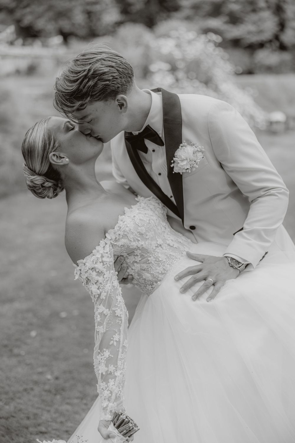 Black and white romantic dip kiss portrait of newlyweds in formal wedding attire.