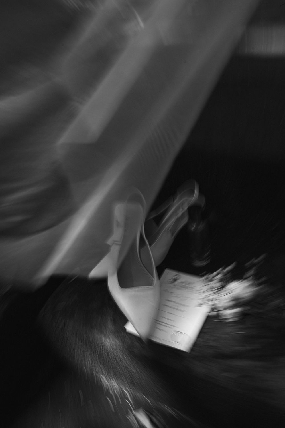 An artistic black and white photograph of a bridal shoe in motion.