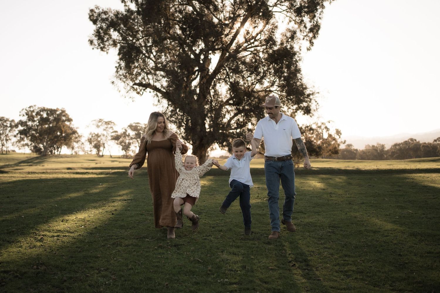 Group of people walking together across a sunlit grassy field on a golden afternoon at sunset in Mansfield