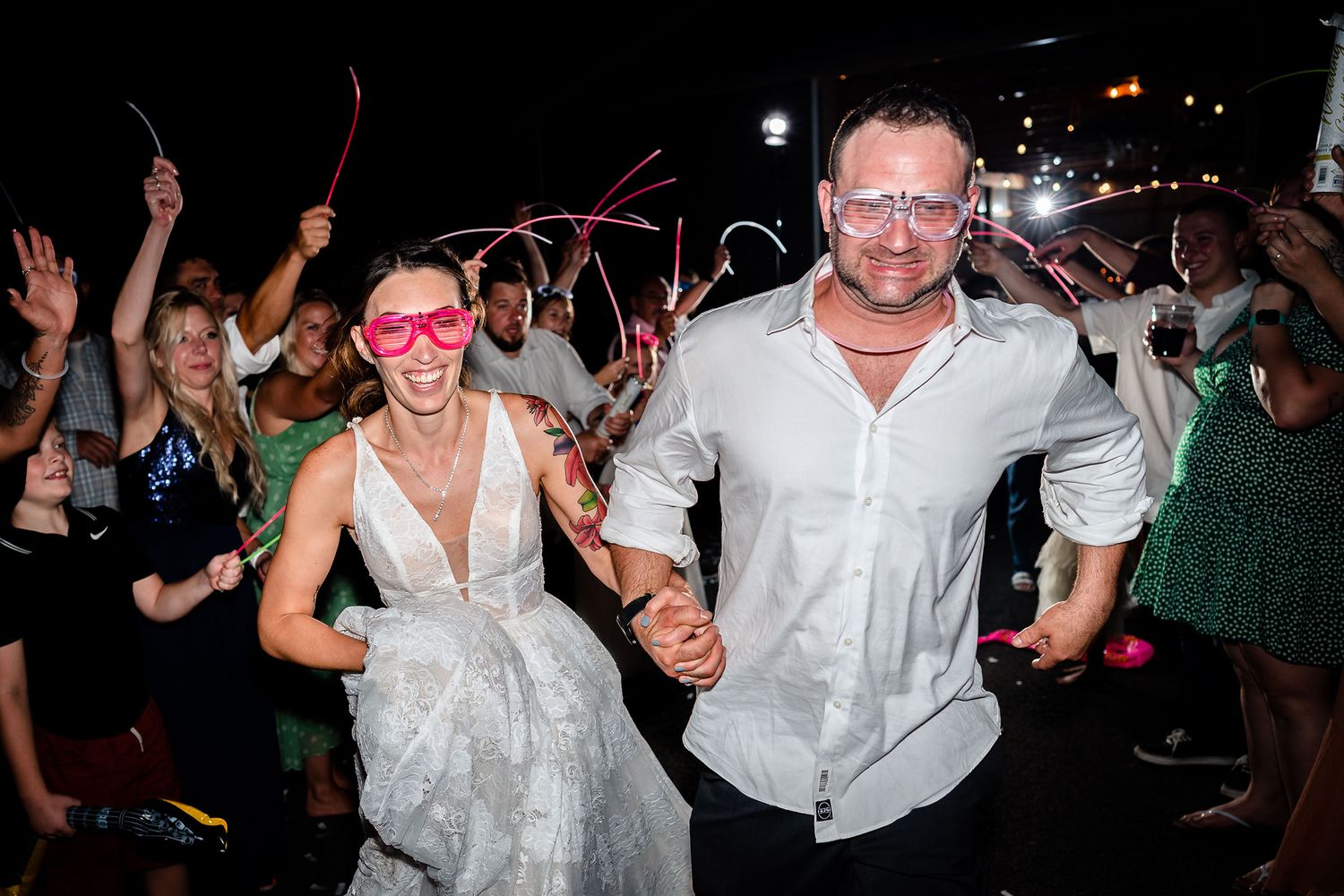 Wedding reception dance party with guests celebrating at night with sparklers and glow sticks.