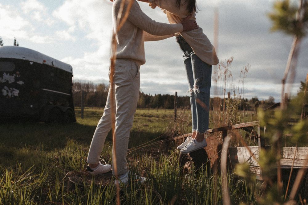 Two people gardening outdoors in a natural setting at sunset with dry grass and plants in the foreground.