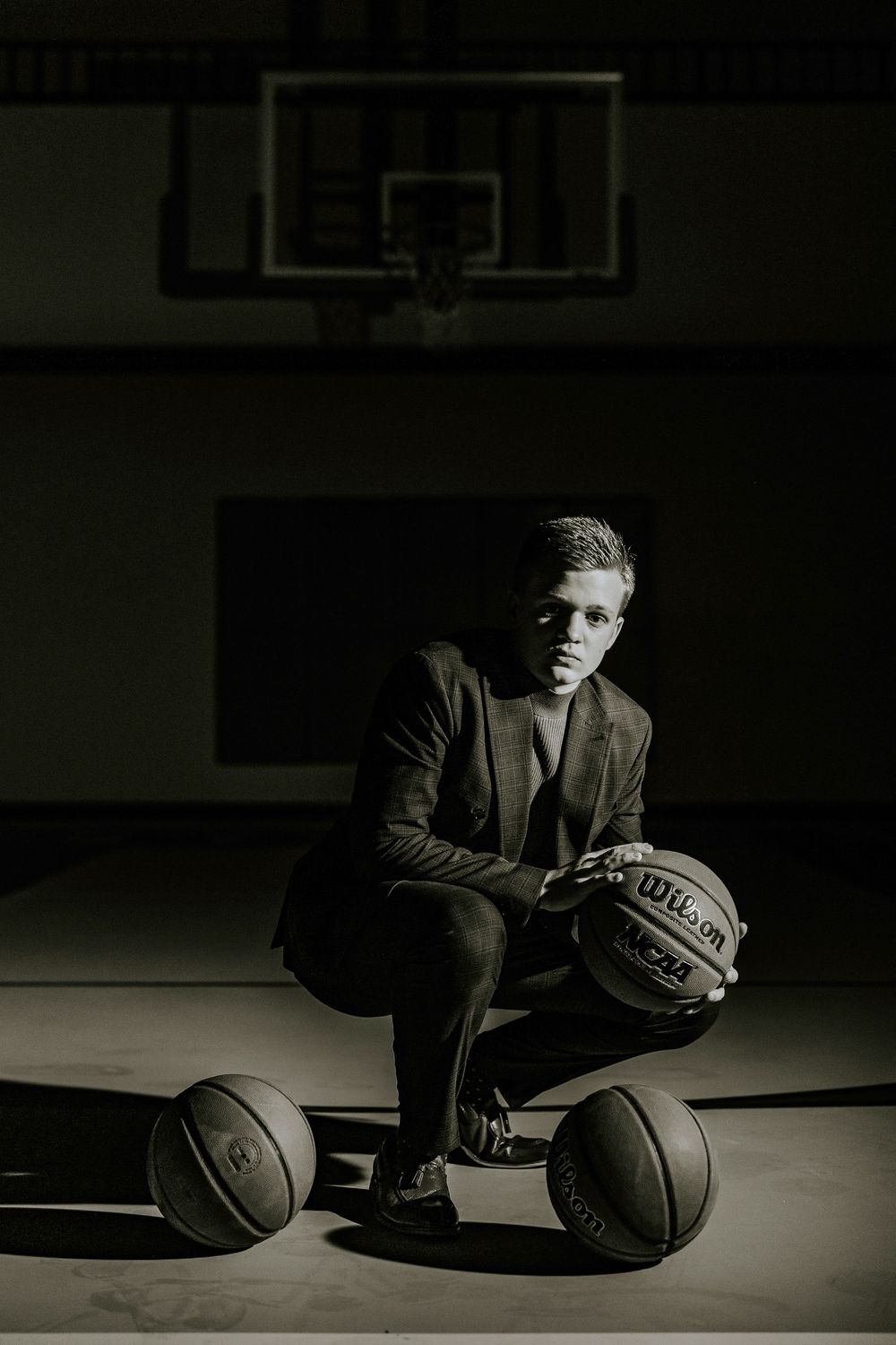 Moody basketball court photo with multiple basketballs and dramatic lighting.
