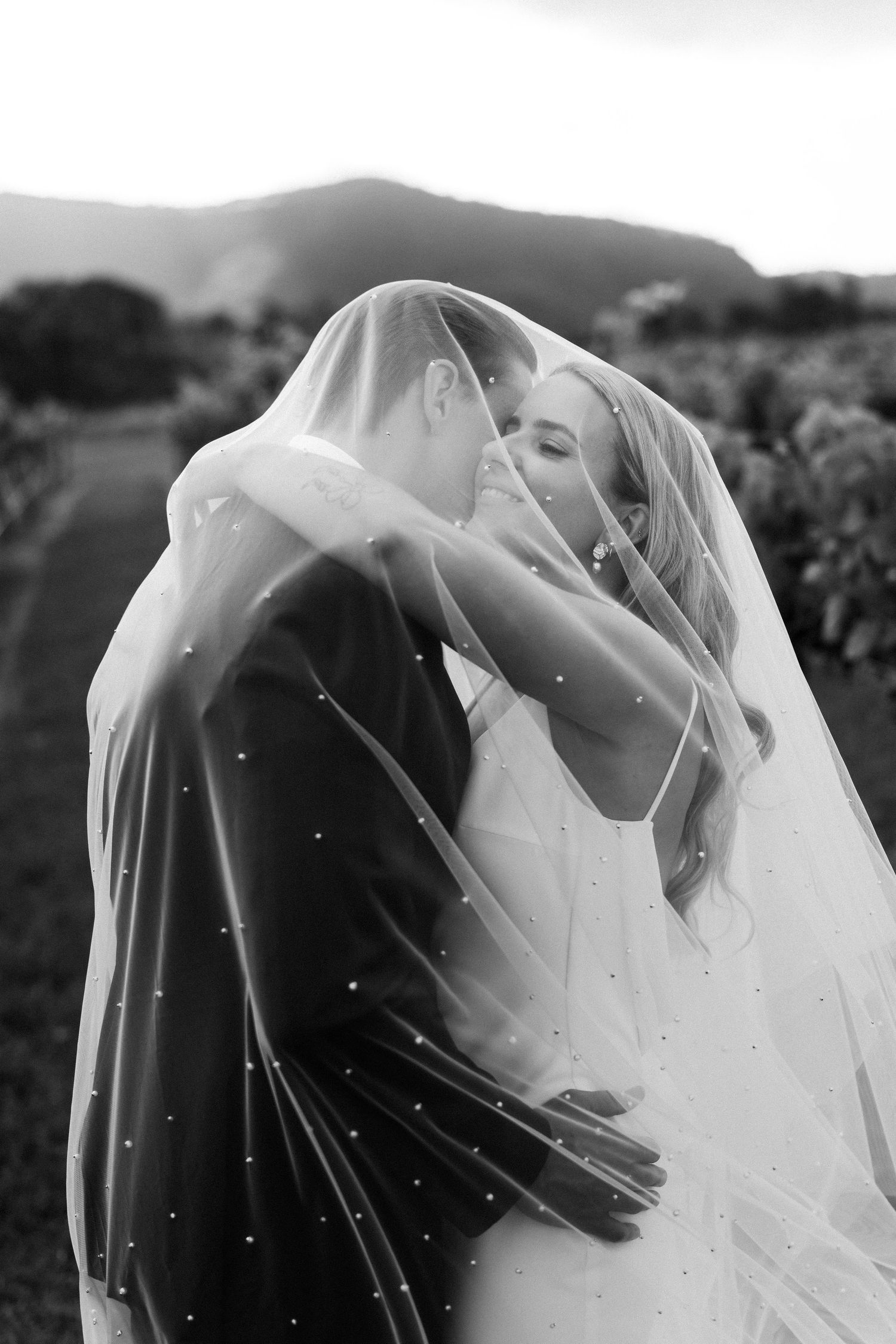 Black and white romantic wedding photo sequence showing tender moments between newlyweds under a flowing veil.
