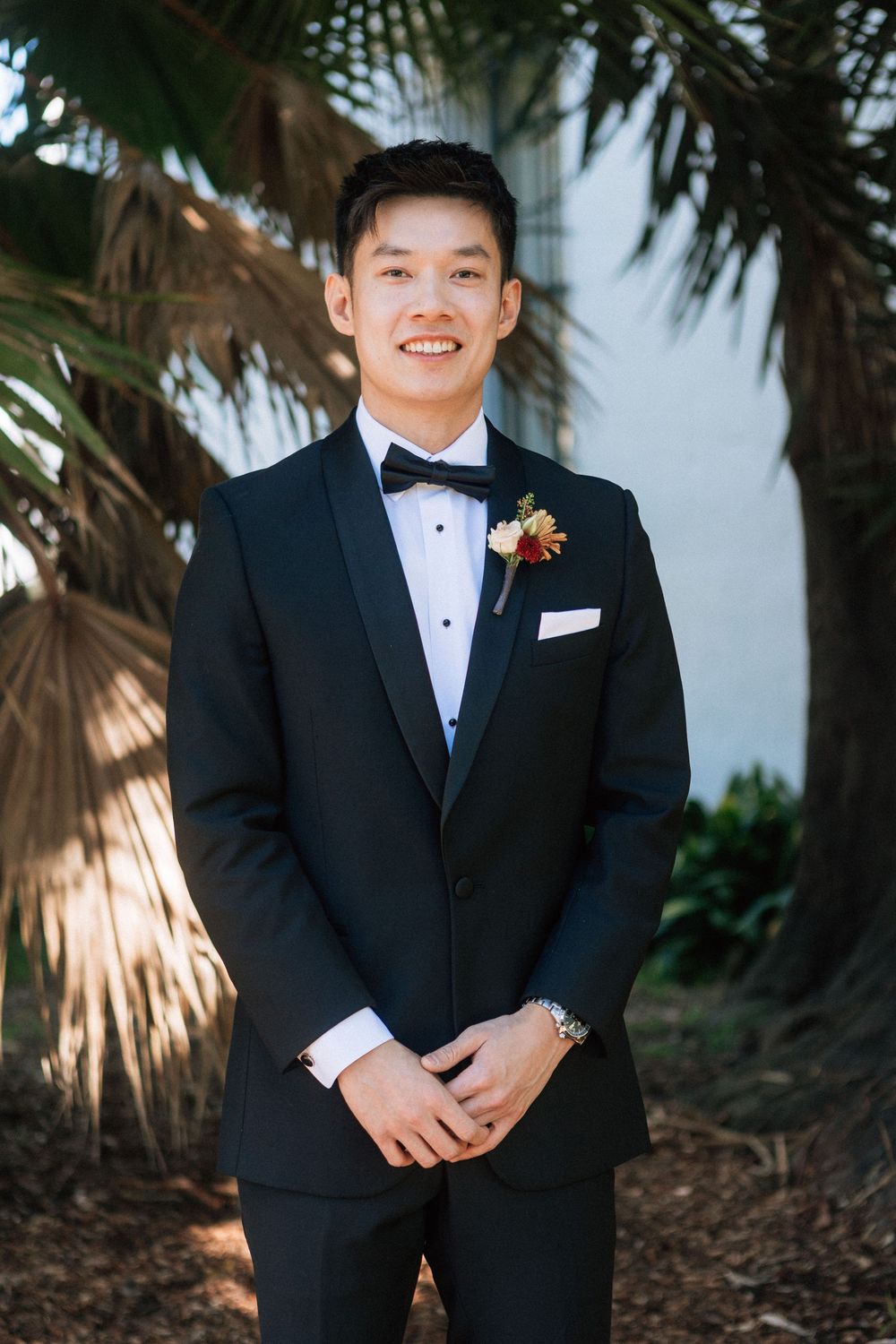 A groom stands and smiles at the camera waiting for his micro wedding at the Santa Barbara Courthouse to begin.