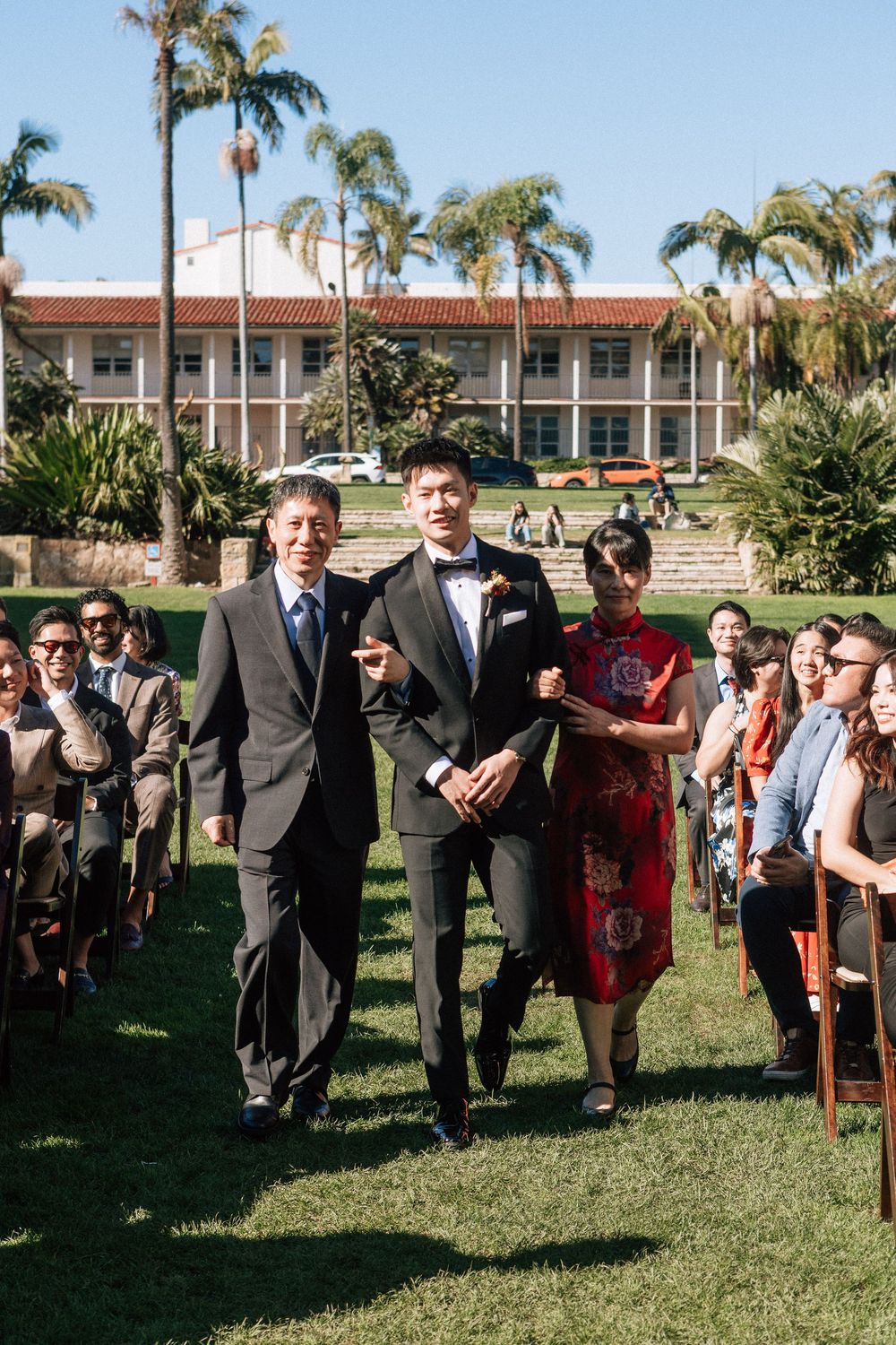 A groom walks down the aisle with his parents before his Sunken Gardens ceremony at the Santa Barbara Courthouse.