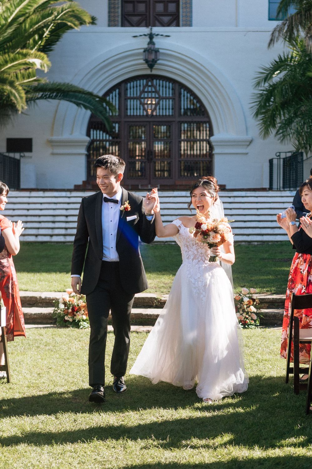 A bride and groom smile and leave the aisle after their wedding at the Santa Barbara Courthouse Sunken Gardens