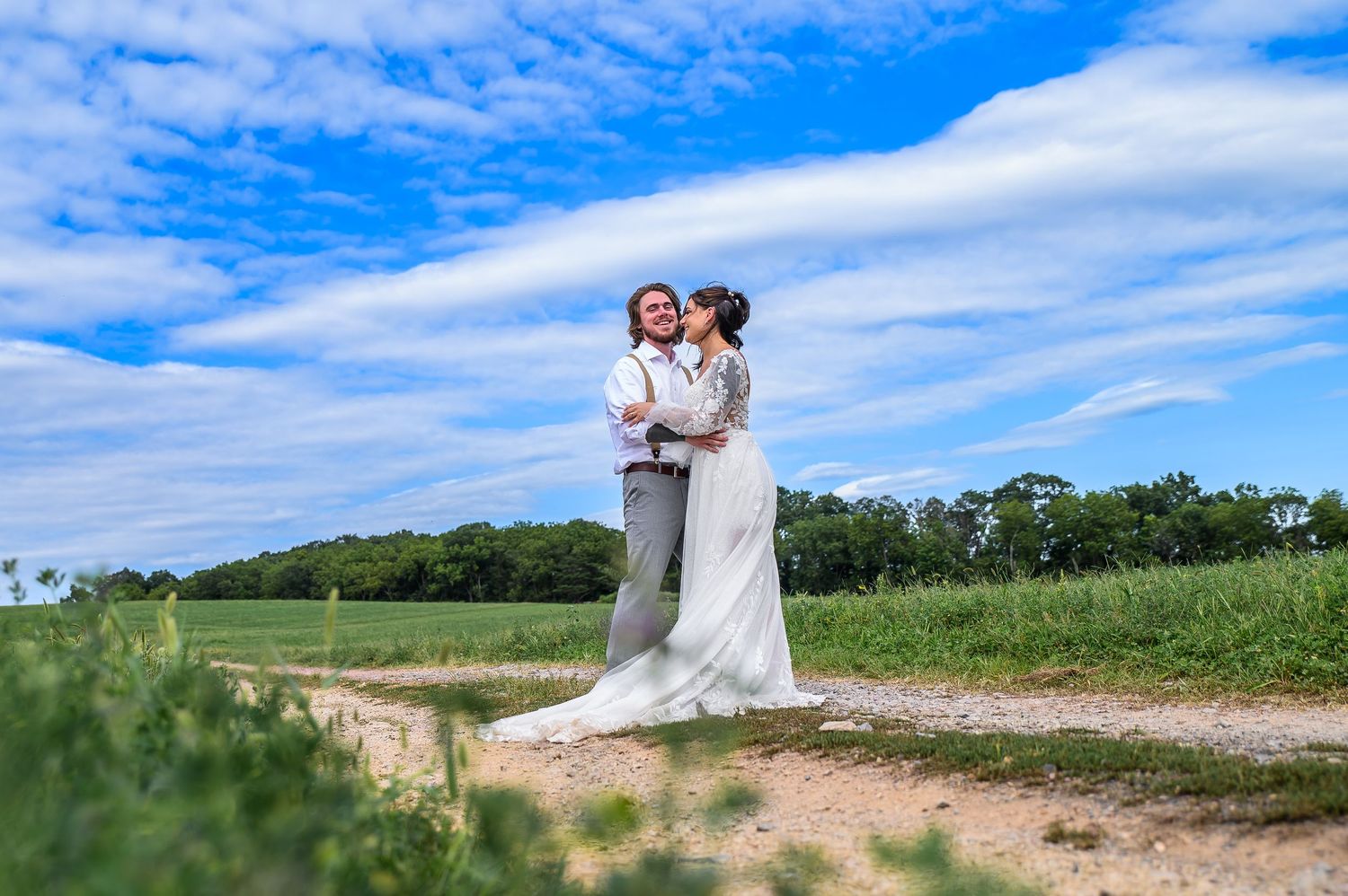 A romantic countryside photoshoot with blue skies and puffy clouds in the background.
