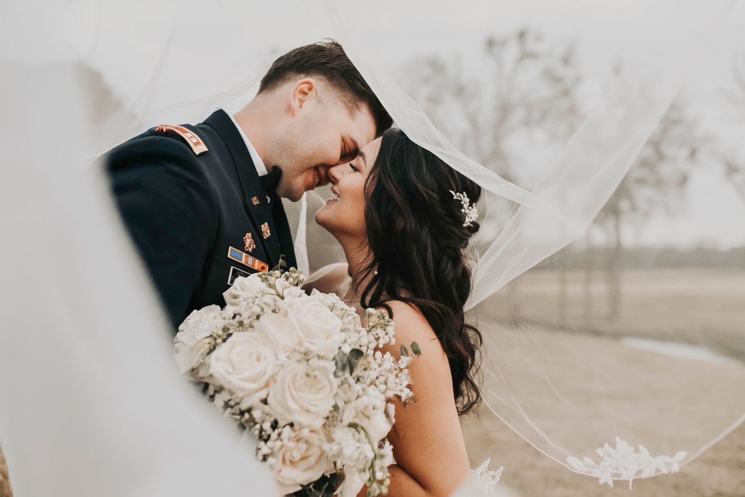 Couple embracing in golden ranch light with sweeping Texas landscape behind them.