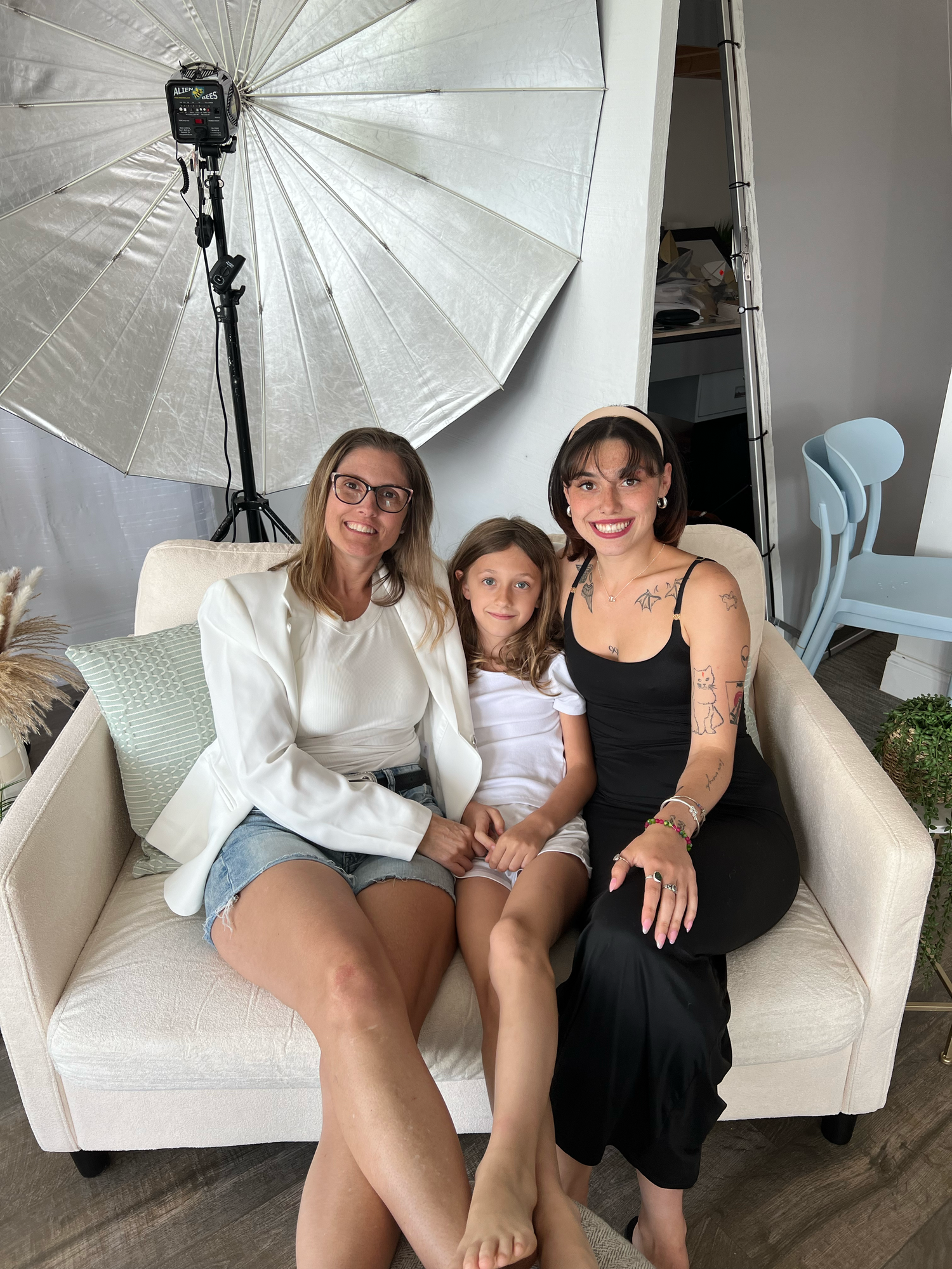 Behind-the-scenes photo shoot setup with studio lighting and white couch.