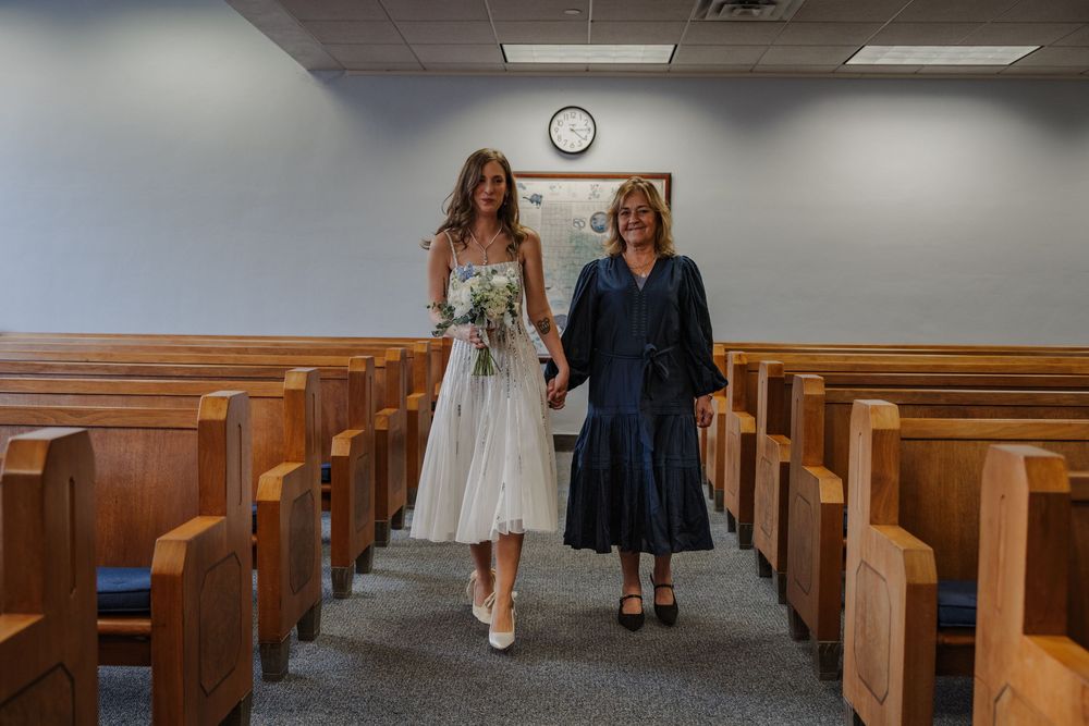 Wedding couple walks down aisle of simple church interior.