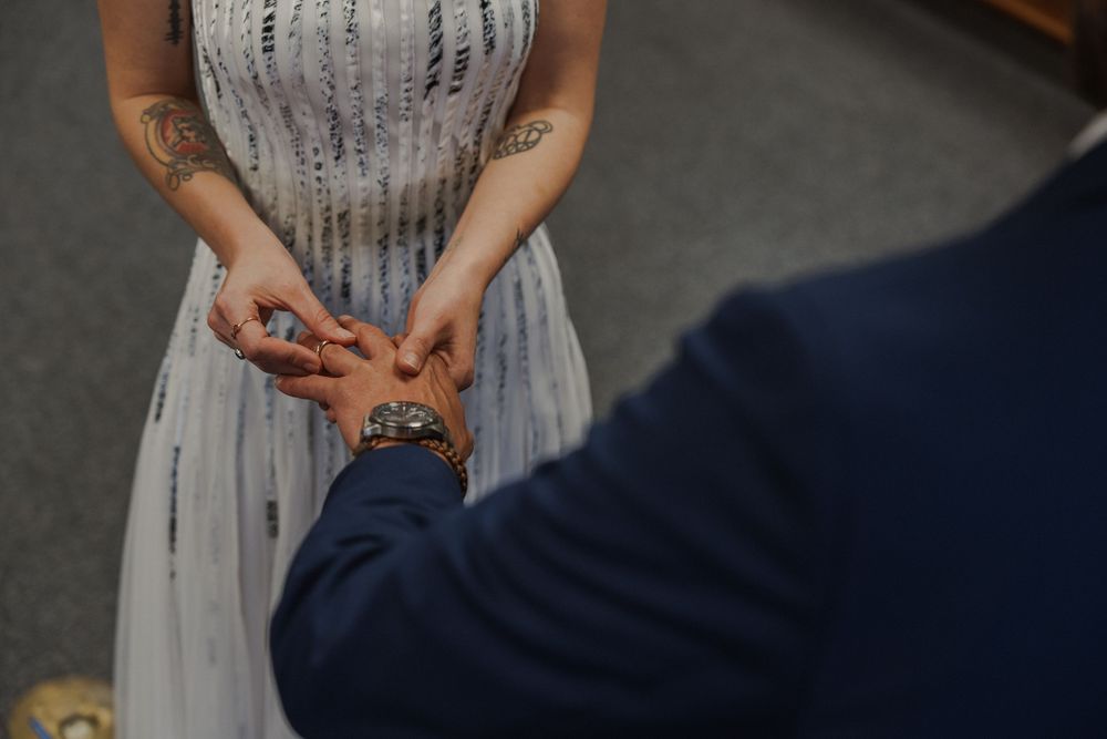 A bride in a silver sequined dress holds hands with her partner during the ceremony.