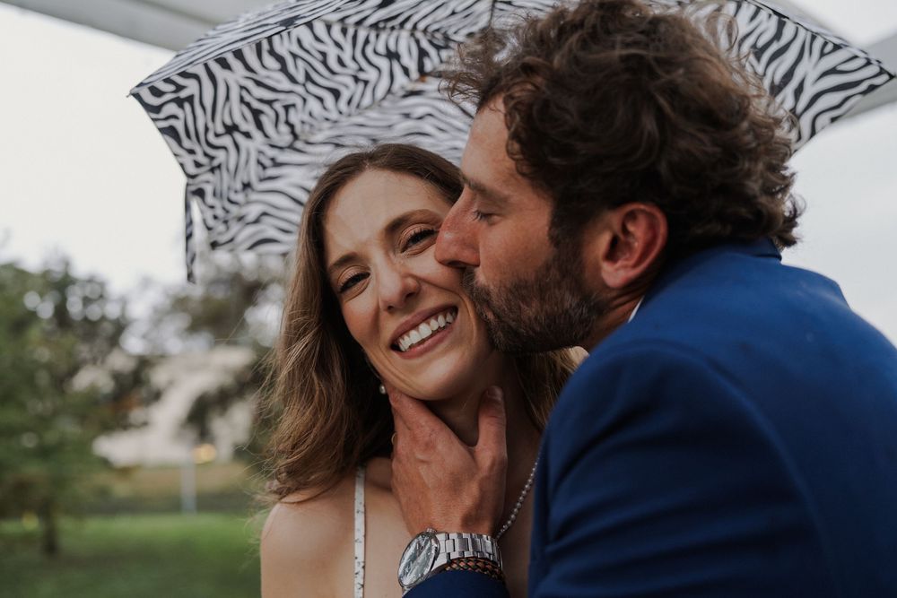 A joyful moment captured between newlyweds sharing laughter under a zebra print umbrella.