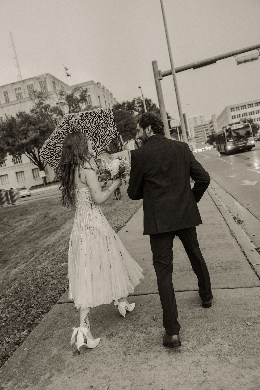 Black and white photo series showing couple walking together on sidewalk in wedding attire.