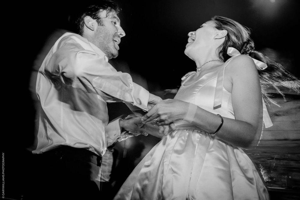 A couple in formal wedding attire dances together during their first dance at a wedding reception.
