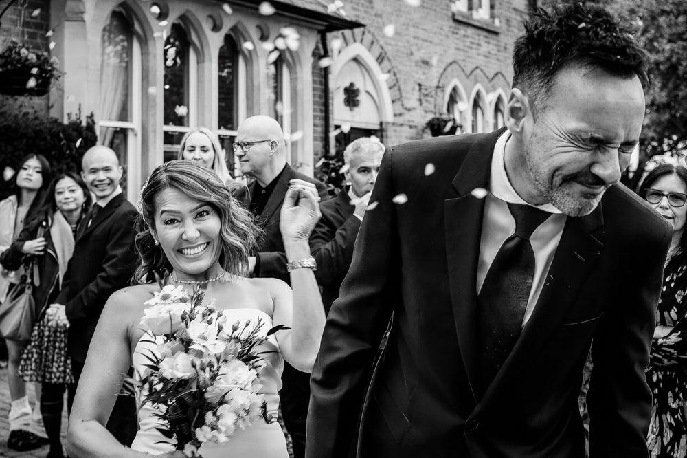 Wedding party celebrates with joy and laughter in a candid black and white moment.