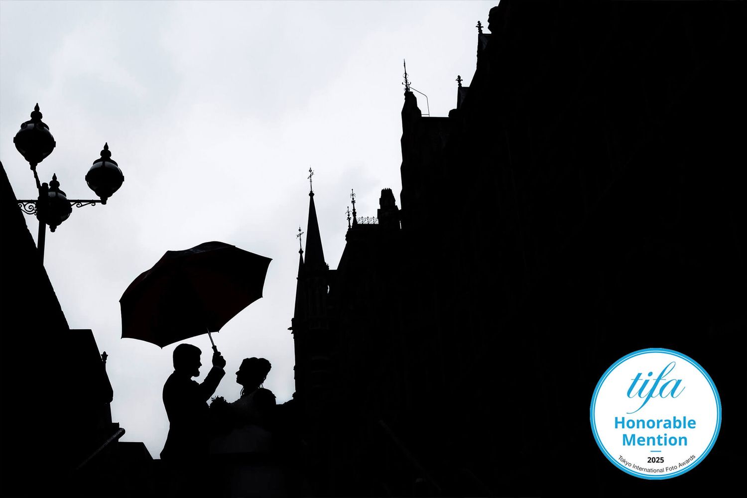 Dark silhouettes of people and buildings against a bright sky create a dramatic urban scene.