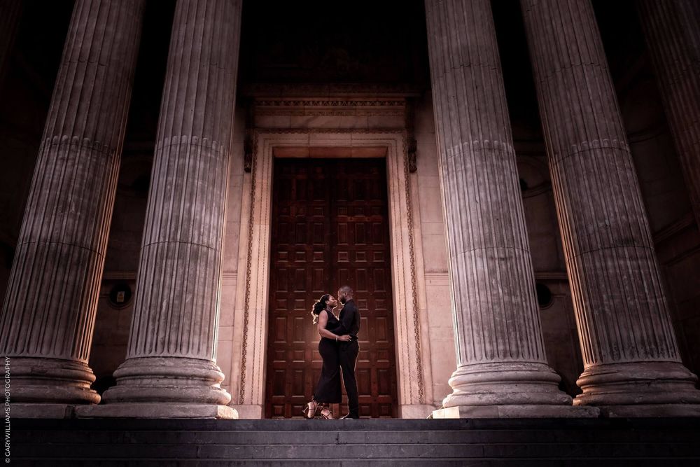 Illuminated neoclassical columns at night create dramatic shadows and perspective at a historic building entrance.
