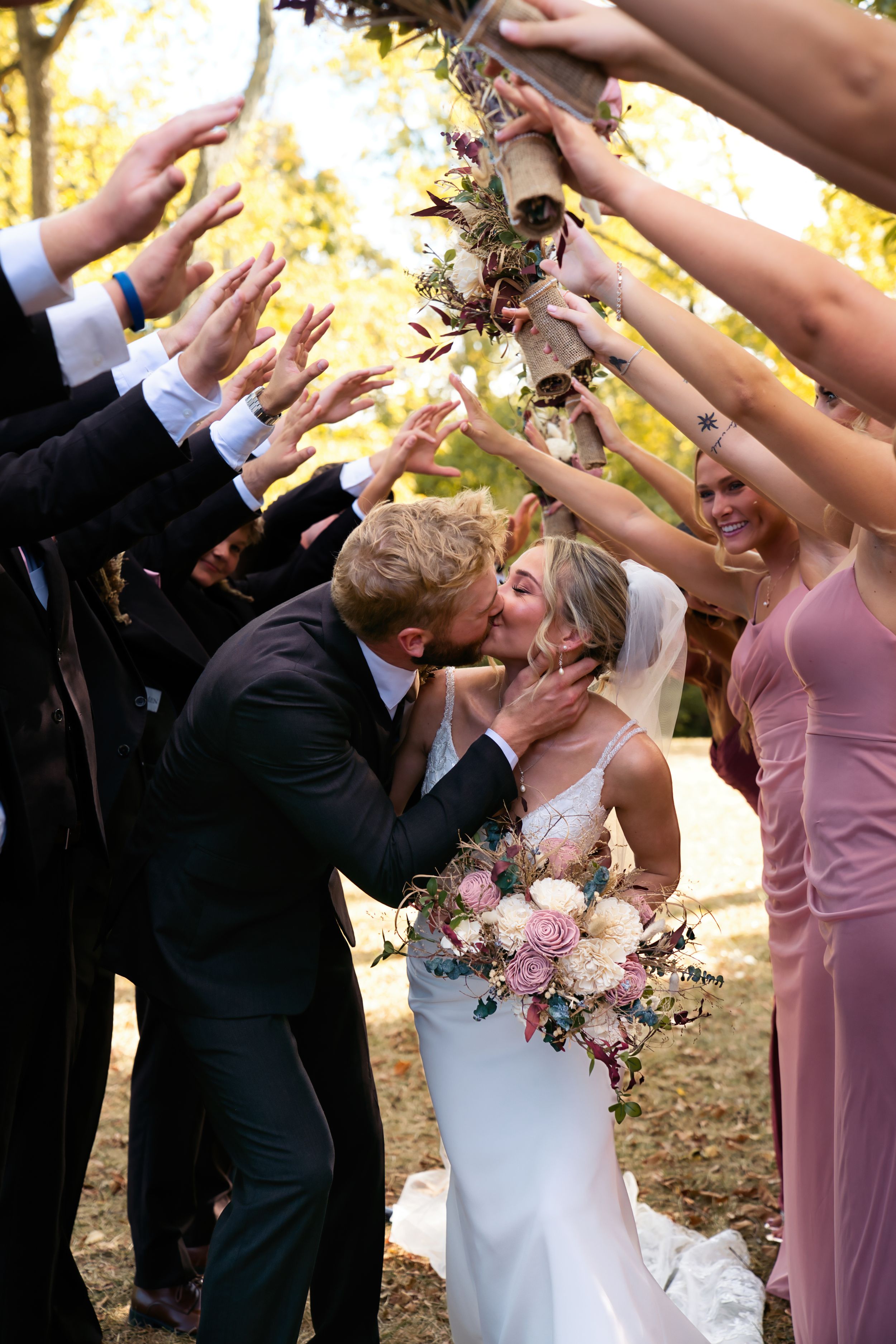 Bride and Groom kissing at sunset during golden hour in Miamisburg Ohio venue with bridal party cheering : Cincinnati Wedding Photographer