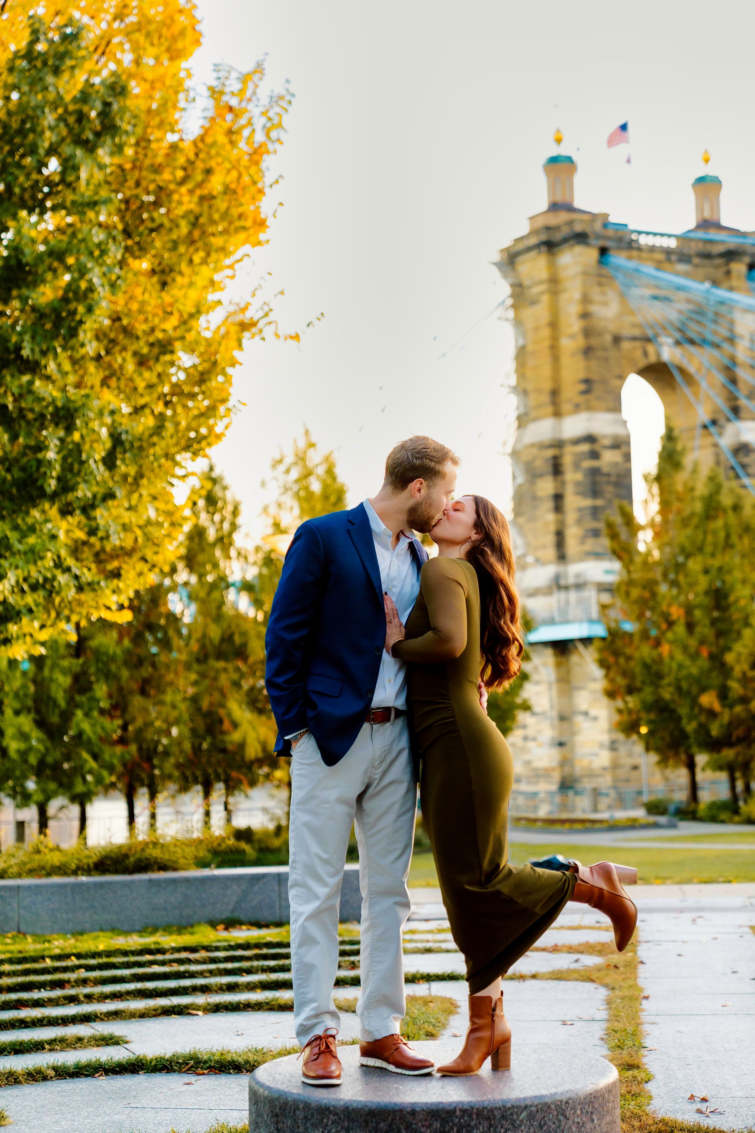 Liz and Chris's downtown engagement at Smale Park in Cincinnati Ohio kissing by the Roebling Bridge : Cincinnati Wedding Photographer