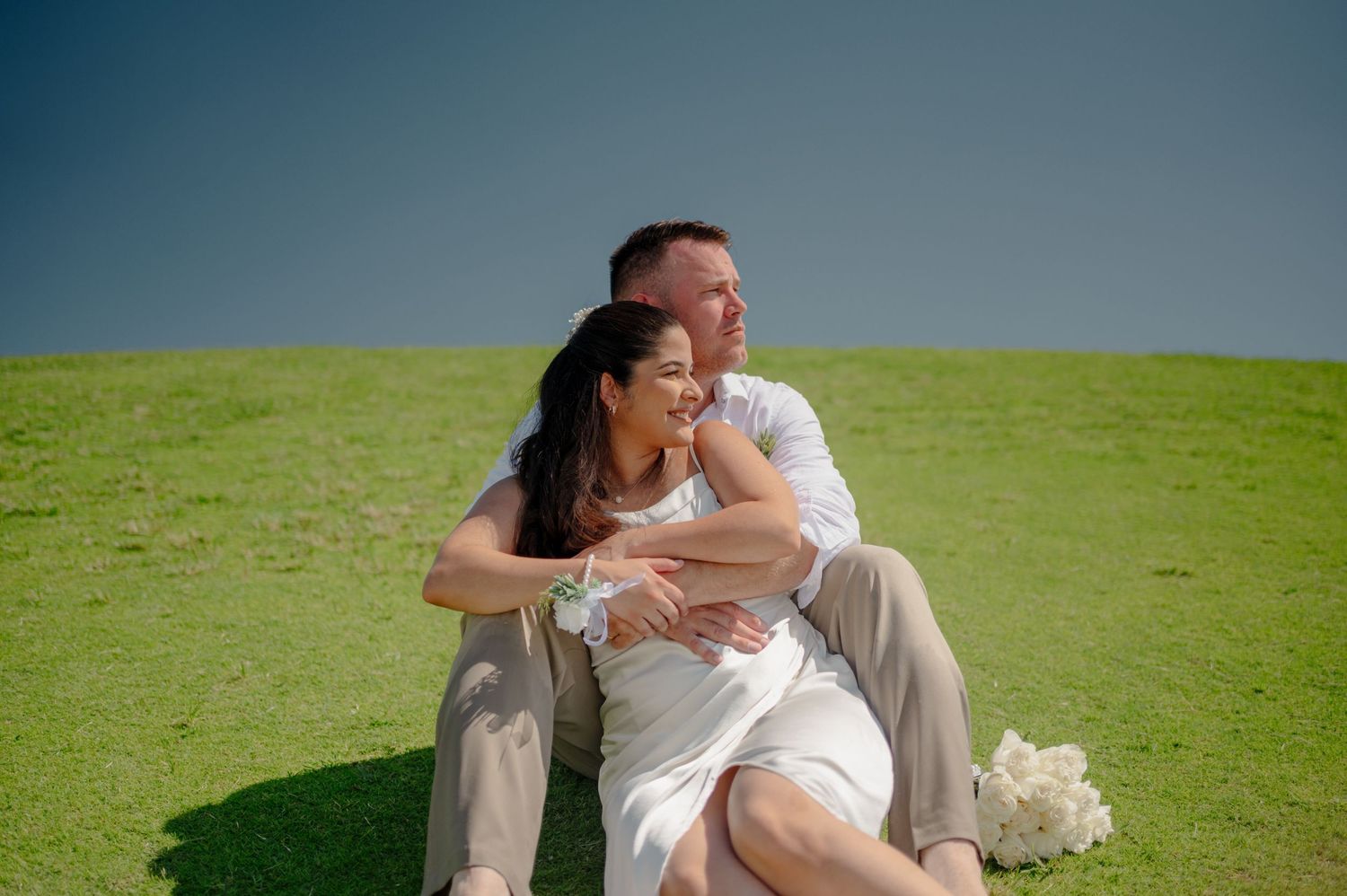 A romantic wedding couple shares tender moments in a series of photos on a lush green lawn.