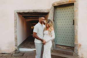 A couple shares an intimate moment together in front of a rustic mint green door and stone archway.