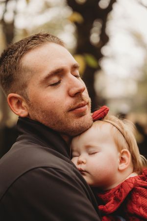 A parent in black jacket shares tender moments with a child wearing red in a series of intimate outdoor portraits.
