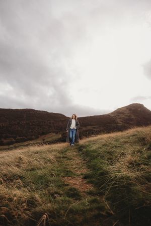 A series of moody landscape photos showing a person walking along misty hillsides on an overcast day in rural terrain.