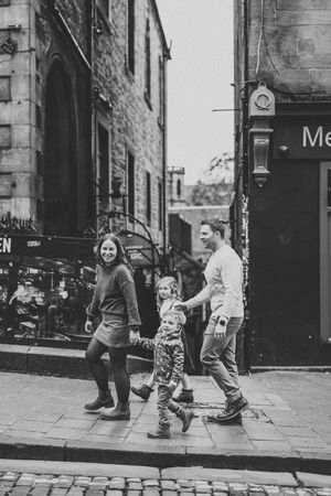 A sequence of black and white photos showing two people dancing playfully on a cobblestone street.