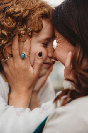 Two women share an intimate forehead-to-forehead moment, one wearing a turquoise ring, both smiling tenderly.