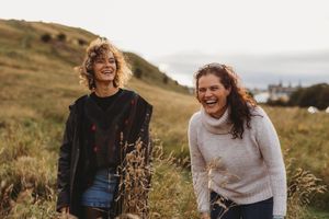 People laughing and enjoying a casual moment together outdoors in a natural setting during golden hour.