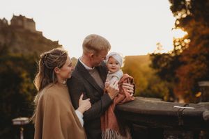 A family shares tender moments during a golden hour photo session in a rustic outdoor setting.