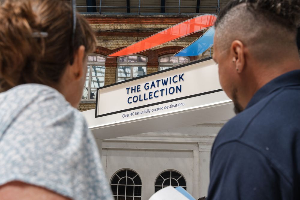 People walking beneath 'The Gatwick Collection' signage in a commercial space.