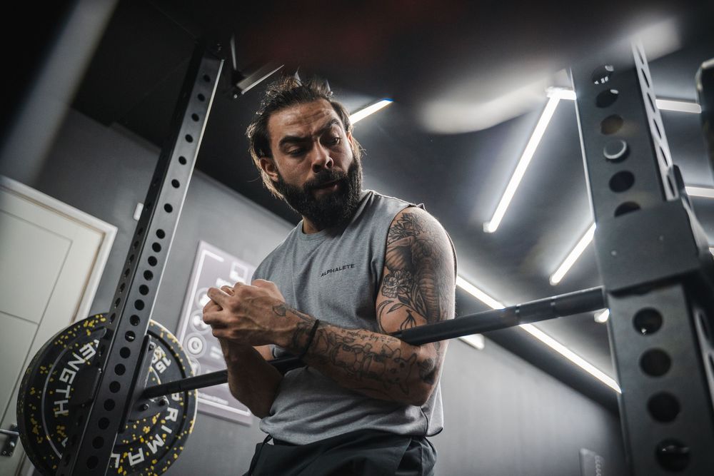 Athletic person with tattoos preparing for workout in modern gym with neon lighting.