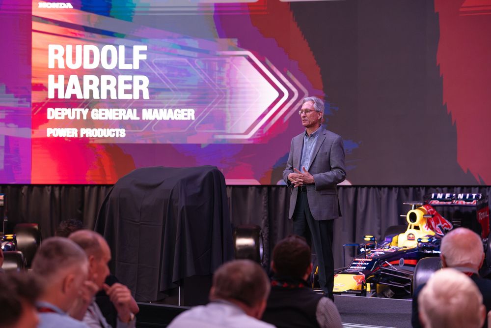 Business presentation showing Rudolf Harrer title card with Formula 1 car display.