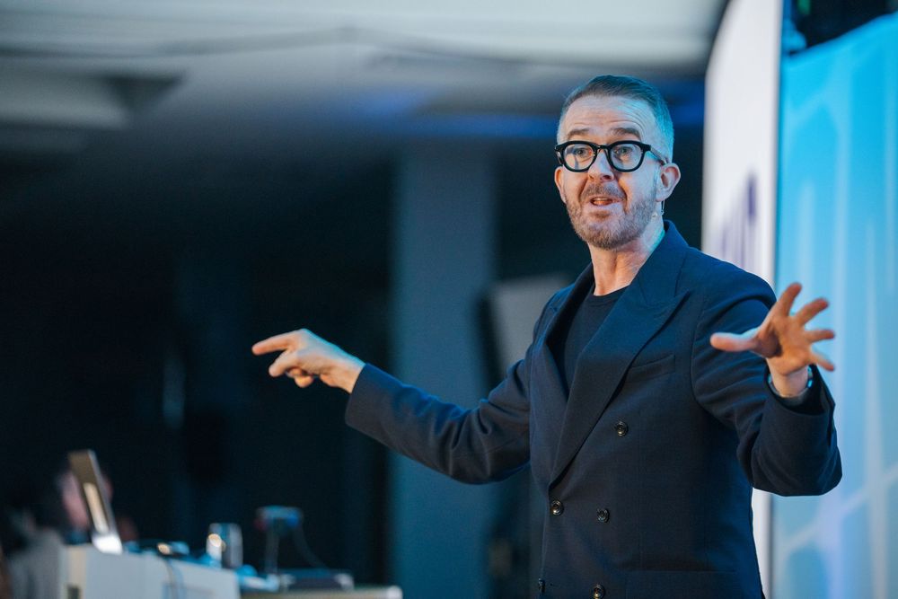 Business presenter gesturing during a keynote speech on stage.
