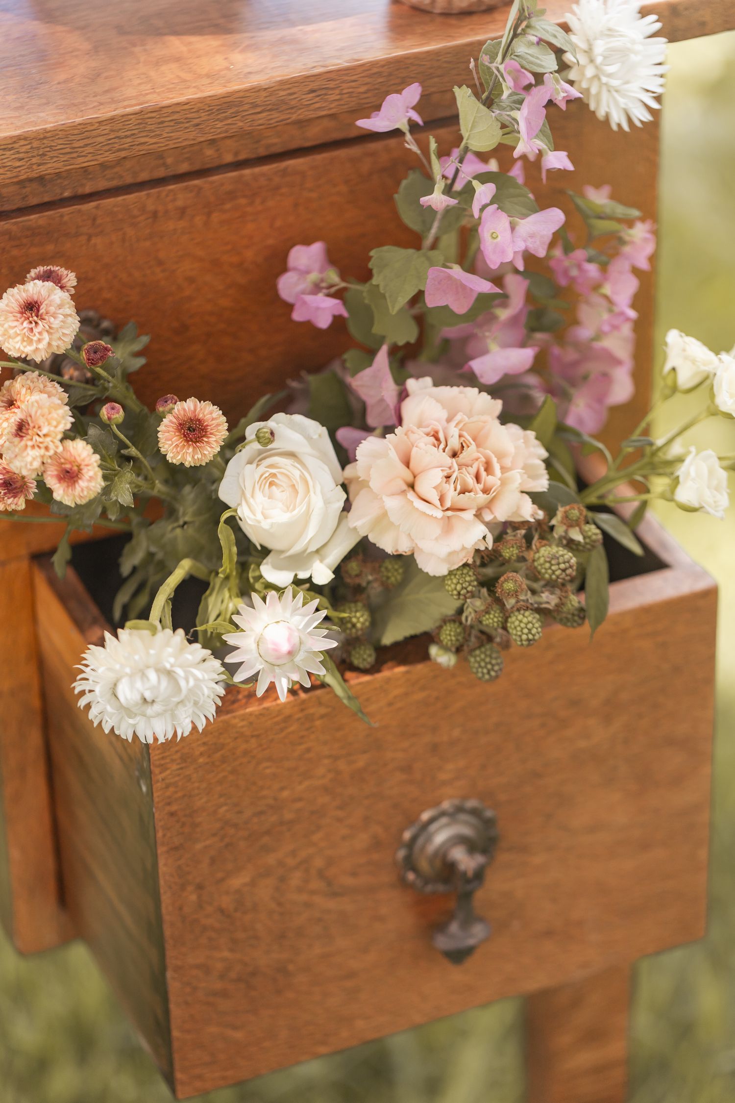 Delicate pink and white flowers arranged in vintage wooden drawers create a romantic rustic display.