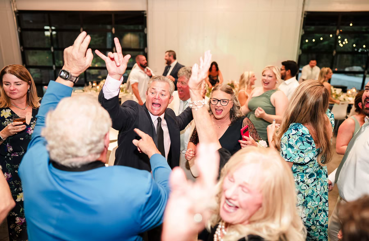 Wedding guests dance and celebrate with raised arms on a festive dance floor in Retreat 21 Wedding Venue