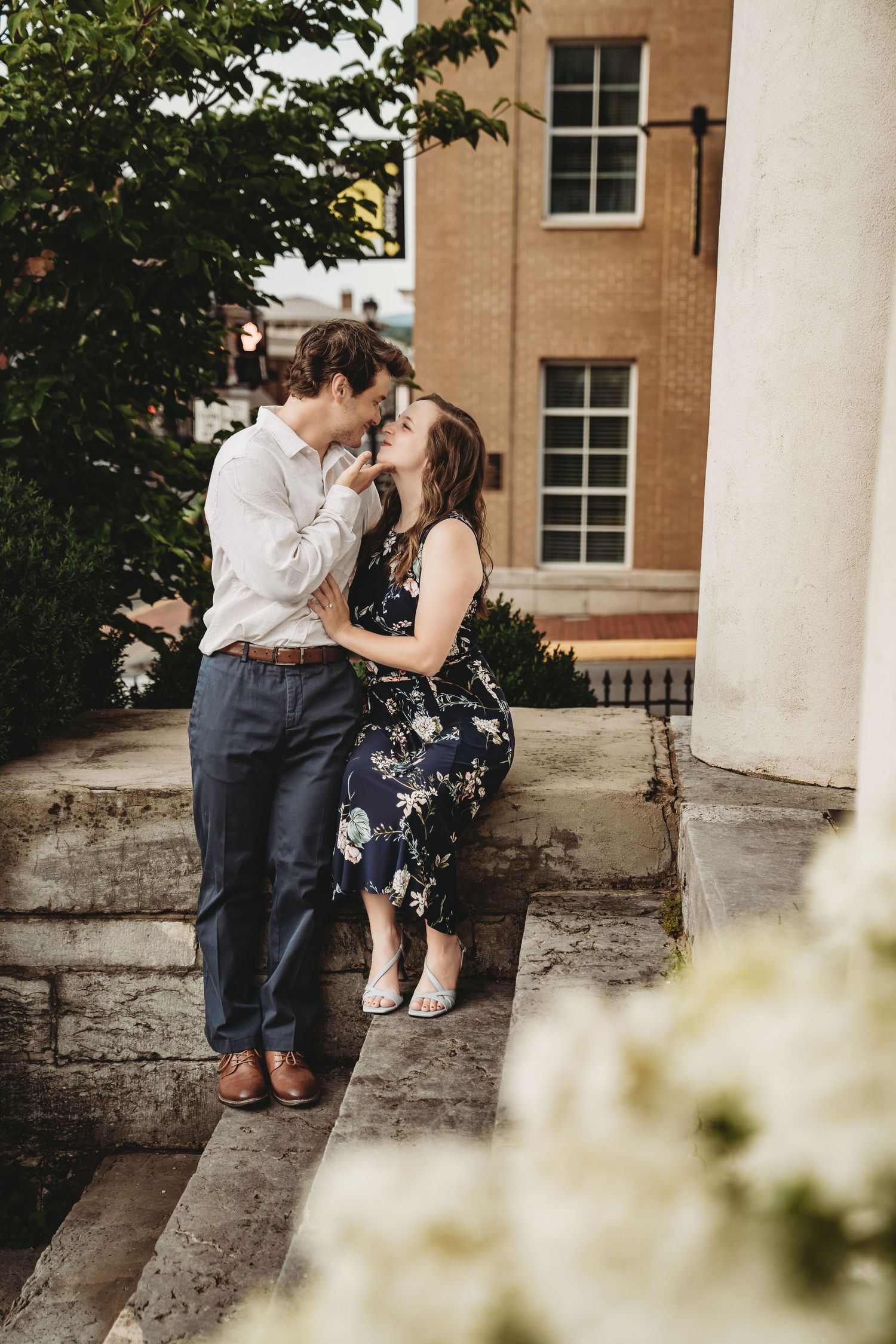 Romantic moment between couple on stone steps near white columns.
