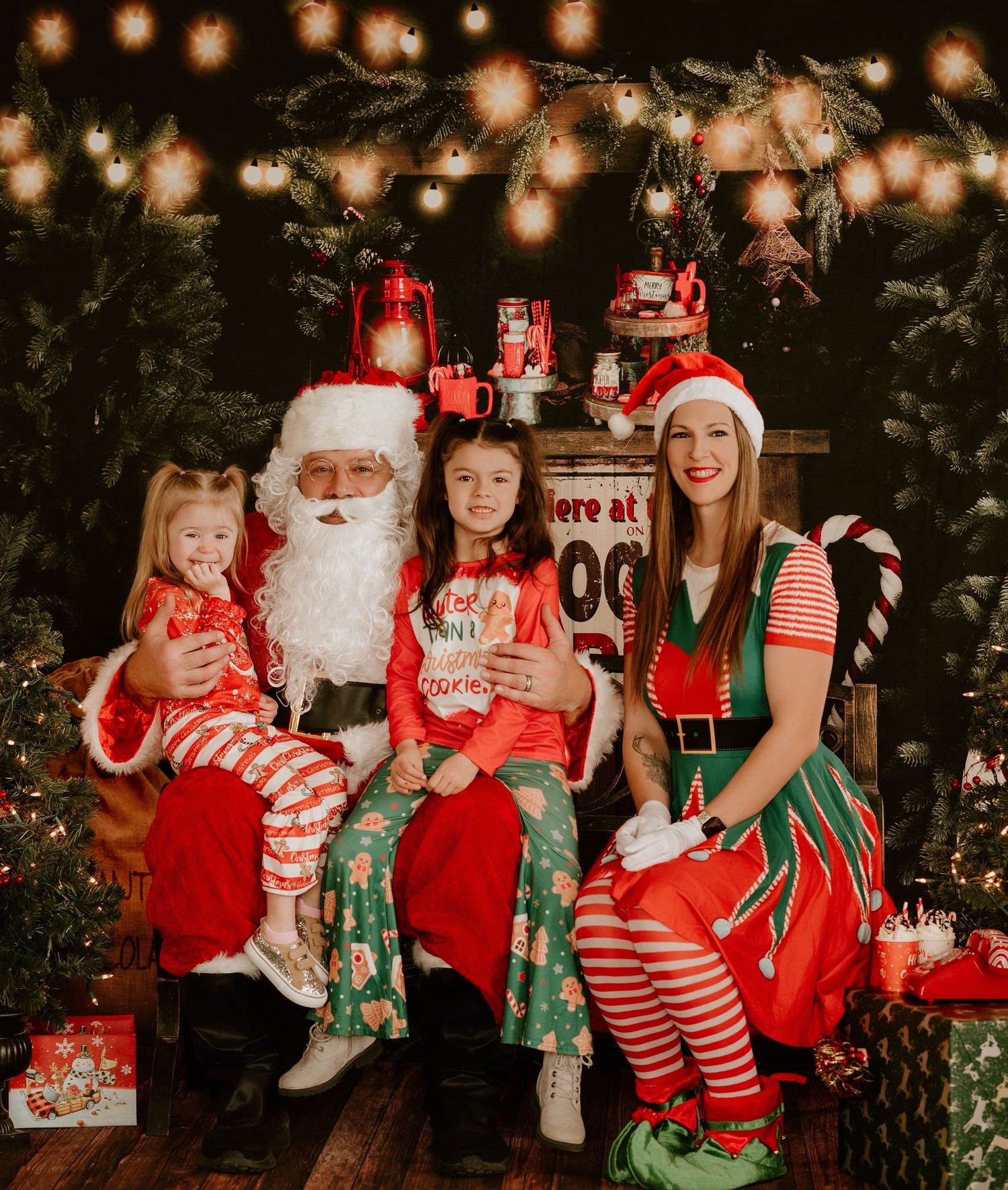 A festive Christmas photo session with holiday lights, decorated trees, and people wearing red and white seasonal outfits.
