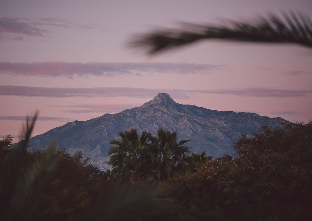 A panoramic series of mountain landscapes at dusk with dramatic purple and pink clouds in the sky.