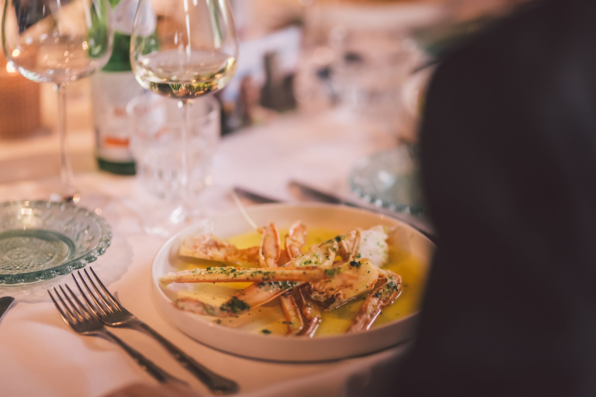 Elegant table settings with wine glasses and plates at a fine dining restaurant in warm ambient lighting.
