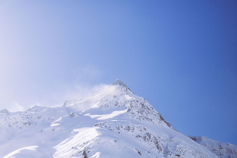 Panoramic view of snow-covered mountain peaks against a bright blue sky on a clear winter day.
